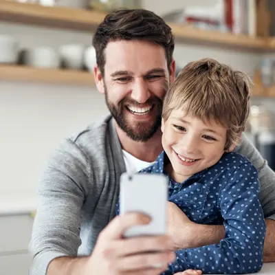 A man and his young son looking at a cell phone.