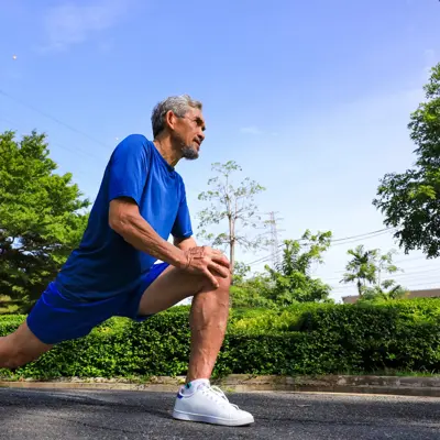 Senior Asian man is stretching his leg muscle during warm up exercise work out in the morning at public park