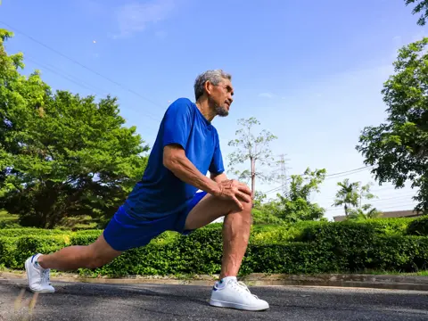 Senior Asian man is stretching his leg muscle during warm up exercise work out in the morning at public park