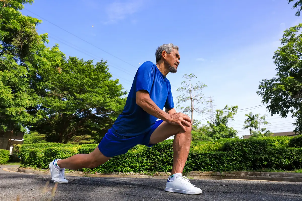 Senior Asian man is stretching his leg muscle during warm up exercise work out in the morning at public park