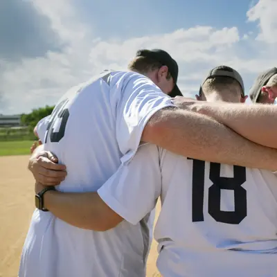 Baseball team huddles together on the field, showcasing unity and teamwork.