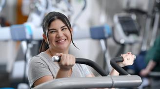 Smiling woman in a gym using a weight machine, showcasing a positive and active lifestyle.