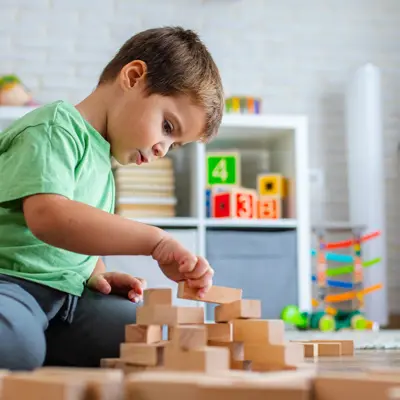 A young boy building with wooden blocks.