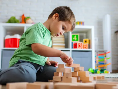A young boy building with wooden blocks.