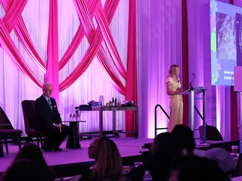 Speaker presenting medical imaging on stage to an audience during a women’s health conference.