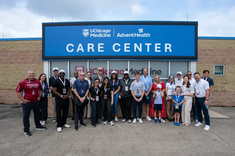Large group of team members and guests pose in front of a UChicago Medicine and AdventHealth Care Center sign outside the building