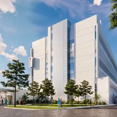 Exterior architectural rendering of the AdventHealth Carrollwood Garden Tower expansion showing a modern multi-story medical facility with white facade, landscaped grounds, ambulance bay, and people walking near the entrance
