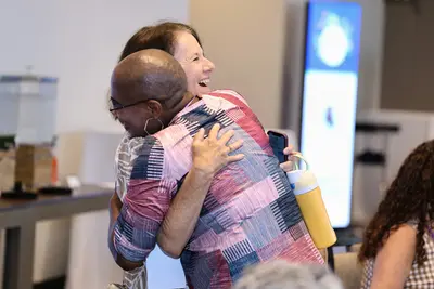Two women sharing a hug and smiling at an event.