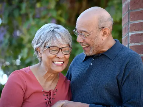 Elderly couple smiling and standing close together, showcasing warmth and companionship.