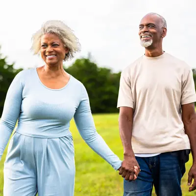 Senior woman and man holding hands outdoors.