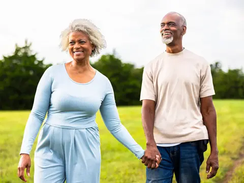 Senior woman and man holding hands outdoors.