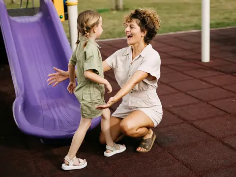 A mother and daughter having fun at a playground.
