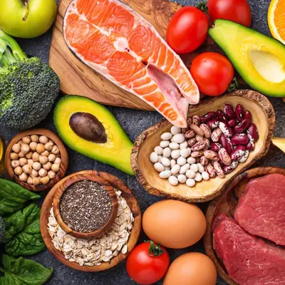 Various fruits, vegetables, nuts, seeds, and meats arranged on a table, showcasing a variety of healthy food options.