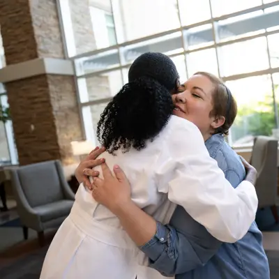 Two women embracing in a hospital setting, conveying warmth and support.